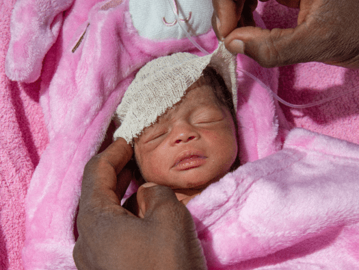 A premature baby wrapped in a pink blanket in Nigeria.