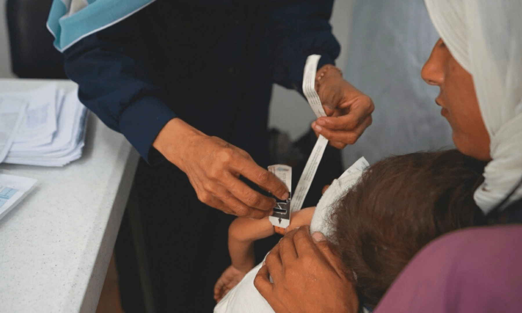 Teams measure a child's arm at MSF's clinic in Gaza City in June 2025. 